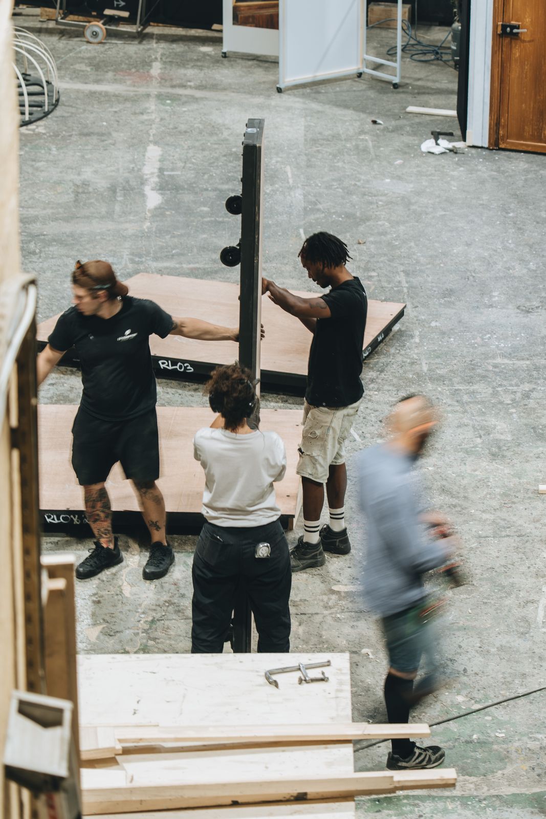 L'équipe déplace un élément de décor dans la cour de l'atelier